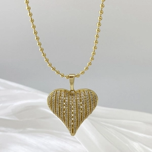 Detailed view of gold striped heart pendant with pavé cubic zirconia on beaded chain