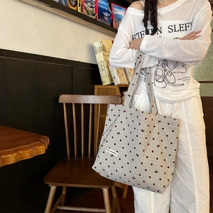 Détail du sac cabas en toile avec pois bordeaux et broderie dans une pièce chaleureuse