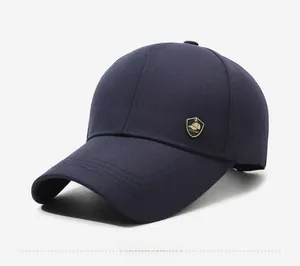 Detail of navy blue cotton baseball cap with a gold fashion emblem and curved visor