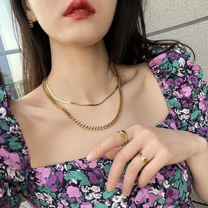 Close-up of layered 18K gold-plated snake chain and Cuban necklace worn by model