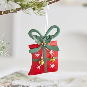 Festive red iron Christmas gift box ornament with green bow hanging on a pine branch