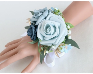 Wrist corsage featuring blue artificial roses and gold leaf detail on a white silk ribbon