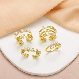 Gold open ring set featuring pearl heart, butterfly and star designs on silk fabric