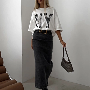 Détail d'un t-shirt blanc en coton imprimé NY avec jupe en jean noire et sac marron