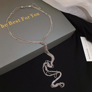 Detail of silver multi-layer chain necklace featuring a knotted tassel design on black velvet