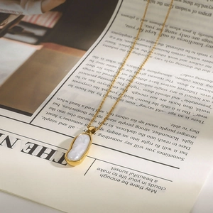 18k goldene Edelstahlkette mit ovalem Perlmuttaufhänger auf Zeitungshintergrund