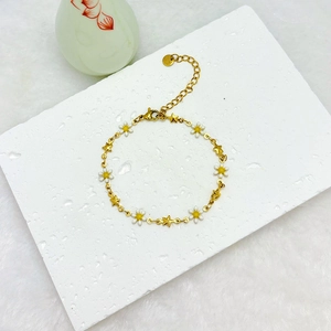 Detail of 18k gold plated stainless steel daisy and star bracelet on stone background