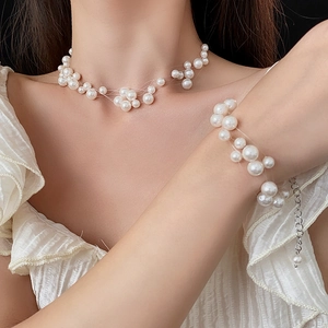 Detail of multi-layered pearl necklace and bracelet set with silver lobster clasp on model