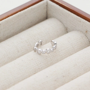Dettaglio macro di ear cuff in argento S925 con zirconi cubici circolari incastonati
