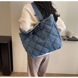 Gros plan sur un sac cabas en denim bleu matelassé avec surpiqûres en losange