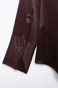 Close-up of deep red satin shirt cuffs featuring silky texture and matching buttons