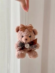 Close-up of a cute plush bear pendant with velvet bows and a silver metal bead chain