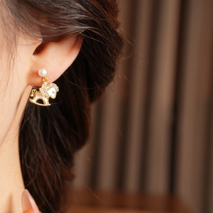 Detail of 14k gold plated rocking horse earring with cubic zirconia and white pearl