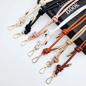Selection of colorful knotted leather bag straps with golden buckles on a black book