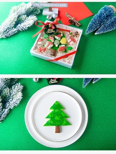 Christmas tree cookies and icing decorations inside a festive gift box with red ribbon