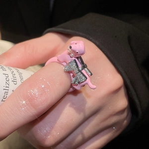 Close-up of a pink enamel dog ring with a zircon bow and pearl necklace detail