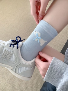 Dettaglio di calzini in cotone azzurro con motivo a cane e fiocco 3D decorativo