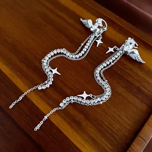 Silver Pegasus earrings with tassel chains and rhinestones on dark wood tray