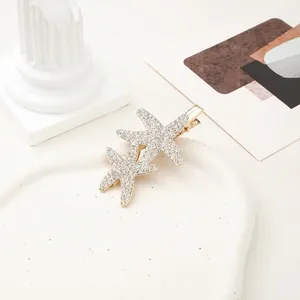 Close-up of elegant double starfish hair clip with white rhinestones on golden base