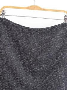 Detailed texture of dark grey tweed fabric on a skirt with subtle speckled pattern