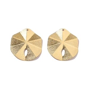Macro detail of two golden sea urchin pendants with matte texture for DIY jewelry