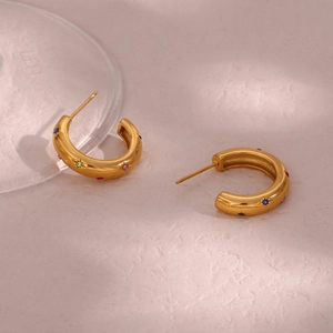Dettaglio degli orecchini a cerchio a C dorati con zirconi multicolori incastonati