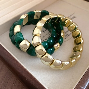 Detailed close-up of acrylic and gold square link bracelets in a luxury jewelry box