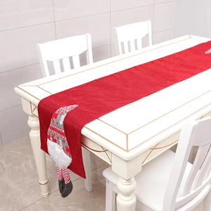 Red Christmas table runner with Nordic gnome dolls on a white modern dining table