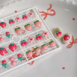 Breloques d'ongles 3D en résine avec motifs de fraises et pêches sur plateau blanc