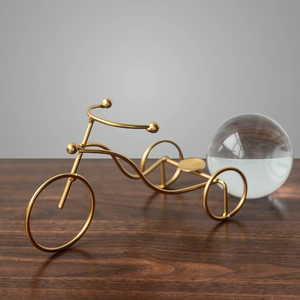 Modern gold metal tricycle ornament with transparent crystal ball on wooden desk