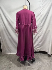 Vista posteriore di un abito boho fucsia con ricamo bianco e bordo con volant