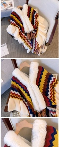 Detail of colorful knitted shawl with white faux fur collar and tassel trim on a chair
