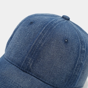 Macro shot of blue washed denim baseball cap showing fine stitching and twill fabric texture