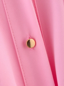 Detail of pink twill fabric with gold metal button and precise double stitching