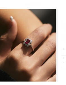 Close-up of a silver ring featuring a rectangular red gemstone with a diamond halo