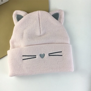 Close-up of pink knit cat ear hat with heart nose embroidery and soft texture