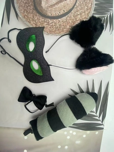 Detailed set of Halloween cat ears, glitter mask, bow tie, and striped tail on tropical background