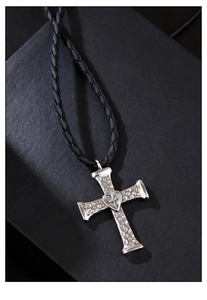 Macro shot of a punk silver cross pendant with heart detail and woven black cord