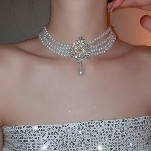 Collier ras de cou en perles avec pendentif goutte incrusté de diamants sur modèle