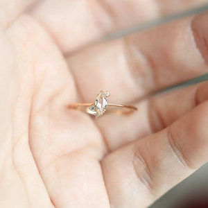 Detail of a thin rose gold ring with marquise-cut center stone and small side diamonds