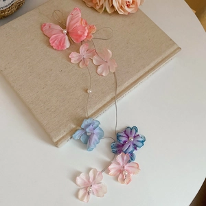Detailed view of the fabric butterfly hair clip with pastel flowers and pearl tassels