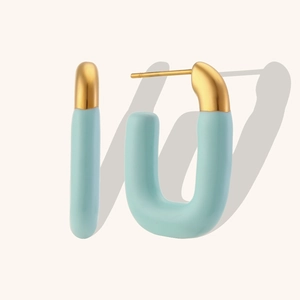 Detail of gold U-shaped earrings with light blue matte enamel finish on solid background