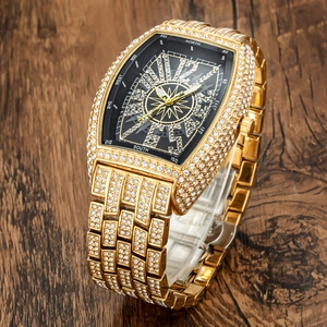 Close-up of luxury gold iced-out tonneau watch with black compass dial on wood background
