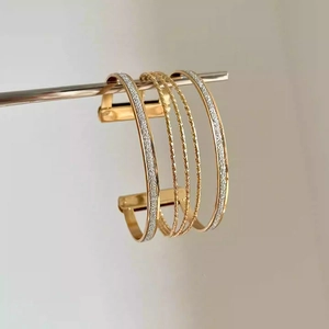 Detail view of gold layered open cuff bracelet with glitter and twisted rope textures
