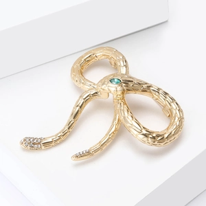 Detailed macro view of a golden snake brooch featuring a green gem and sparkling rhinestones