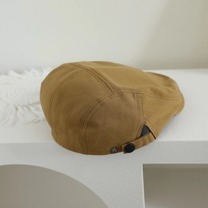 Détail de la boucle réglable en métal sur le béret en coton kaki avec texture sergée
