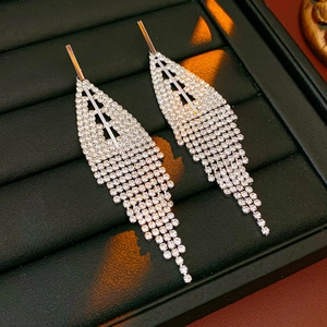 Macro shot of silver tassel earrings with sparkling rhinestones on a black leather tray