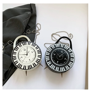 Detail of round handbag with piano keys and clock design including silver chain strap