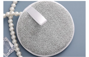 Detail of grey bamboo charcoal facial cleansing puff with white ribbon loop and soft texture