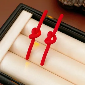 Minimalist red knotted stud earrings displayed in a black premium jewelry box